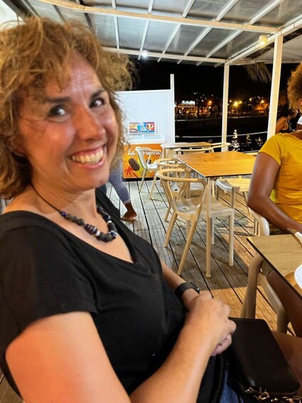 En person sitter vid ett utomhusbord med en stadsbild i bakgrunden. 4