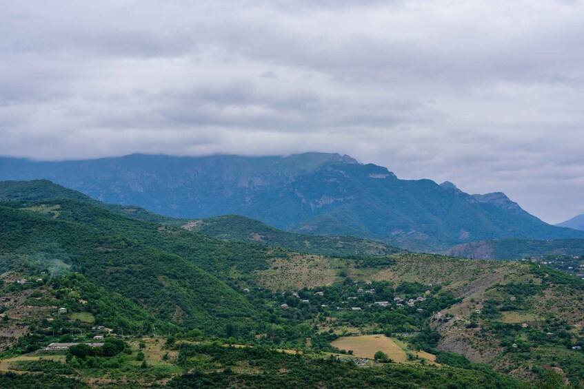A mountainous landscape with dense green vegetation and scattered houses. 5