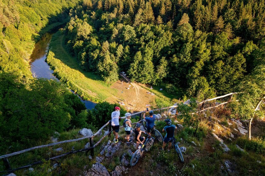 A group of cyclists on a mountain trail with a river in the background. 4
