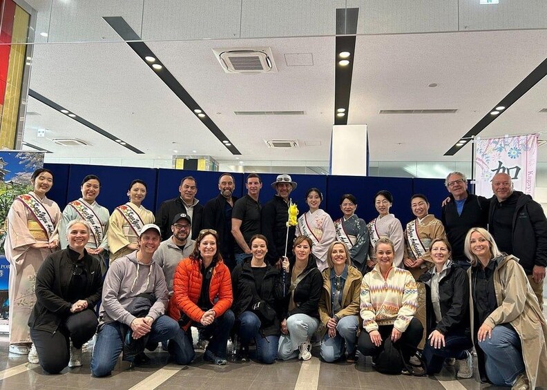 A group of people posing for a photo in a modern indoor setting with blue partitions and recessed lighting. 3