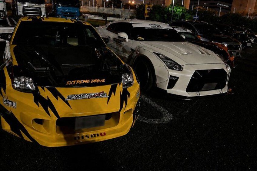 Dos coches deportivos modificados estacionados en un estacionamiento durante la noche. 5