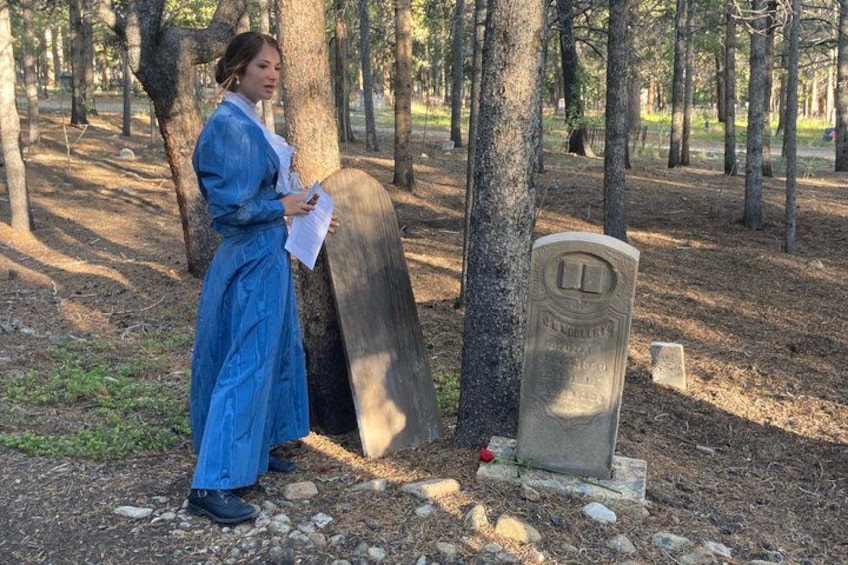 A person standing next to a gravestone in a wooded area. 2