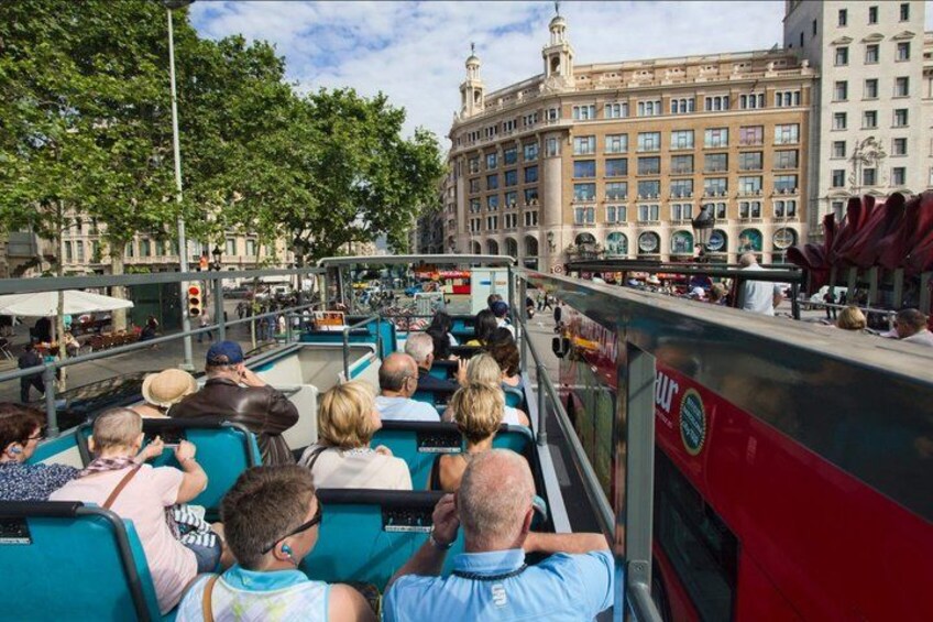 A tour bus with passengers, a large building with classical architecture, and a tree-lined street. 2