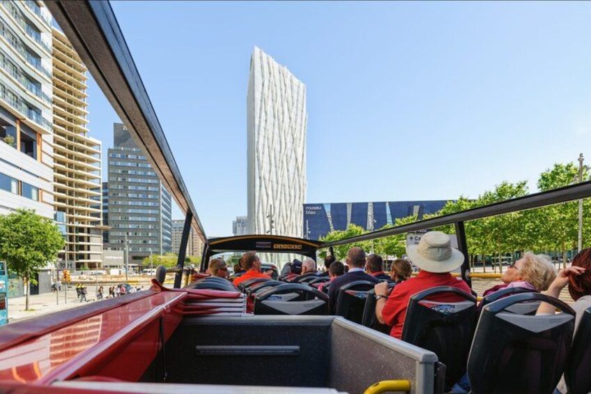 A group of people on a bus, a tall building, and a bridge. 1