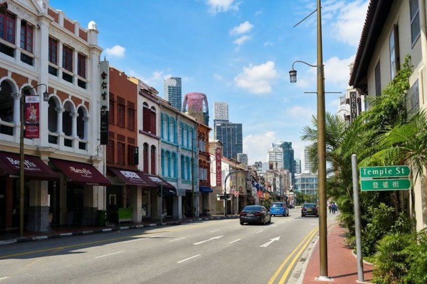 A street lined with colorful buildings, a clear sky, and a street sign for Temple St. 3