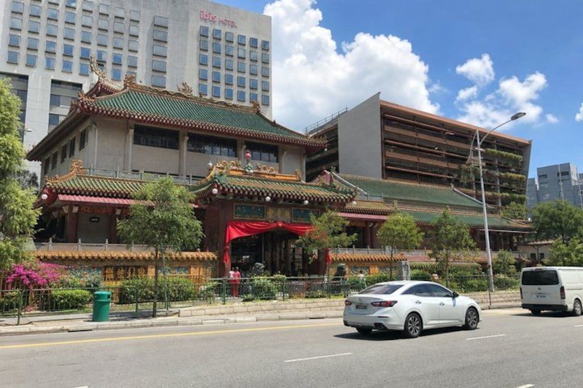 A traditional Chinese building with a modern structure, a white car, and a van on the street. 2