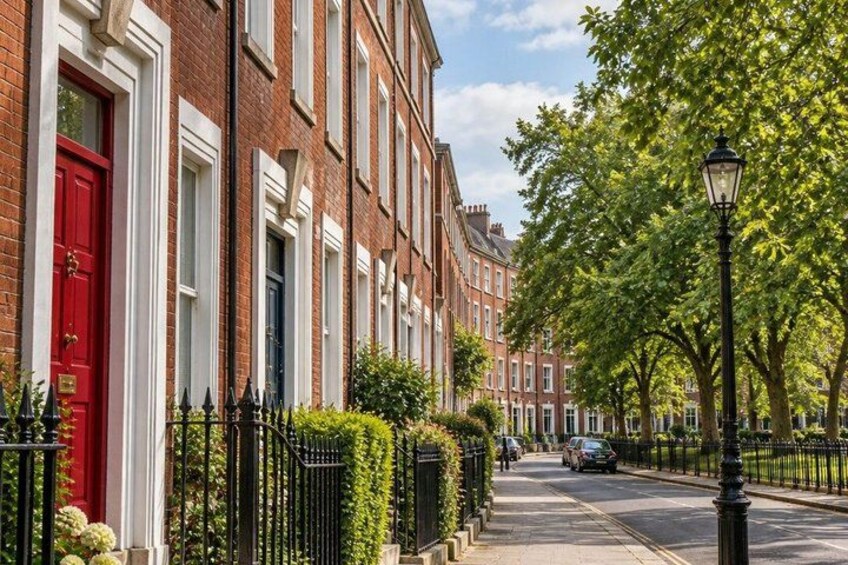 A row of red-brick townhouses with white window frames, a black metal fence, and a street lamp. 5
