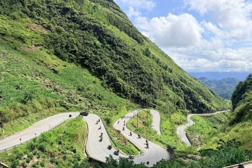 A winding mountain road with vehicles and cyclists. 2