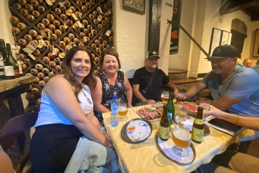 A group of people seated at a table with a wine rack in the background. 2
