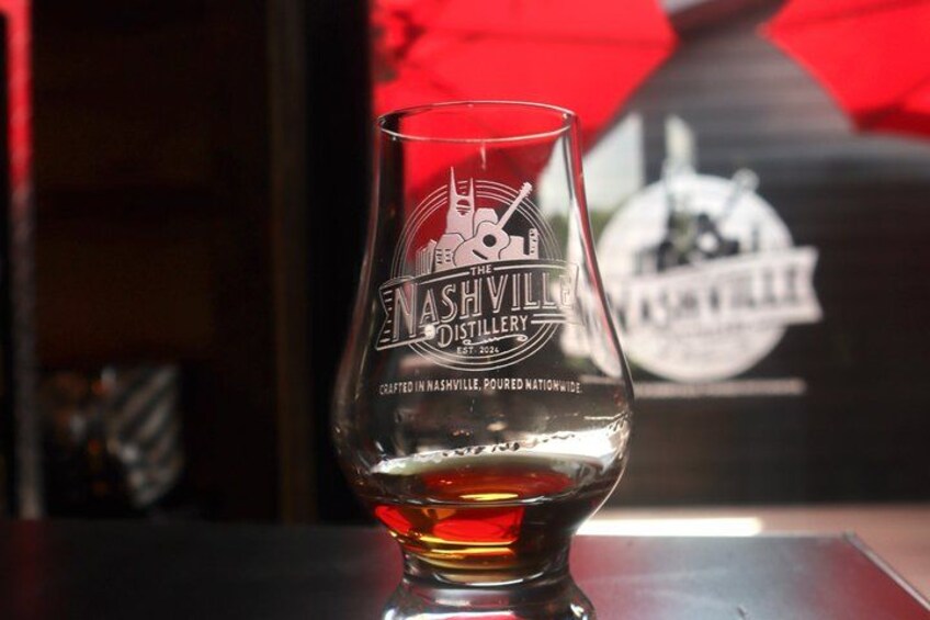 A glass of whiskey with a logo of Nashville Distillery on it. 1