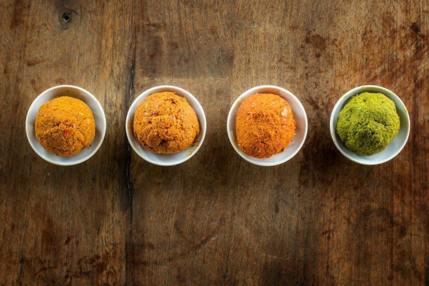 Four bowls of different colored powders on a wooden surface. 4
