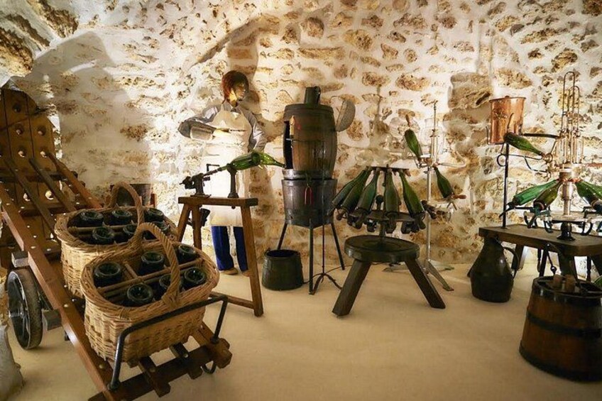 A rustic kitchen with stone walls, a wooden chair, a basket of bottles, and vintage kitchen equipment. 4