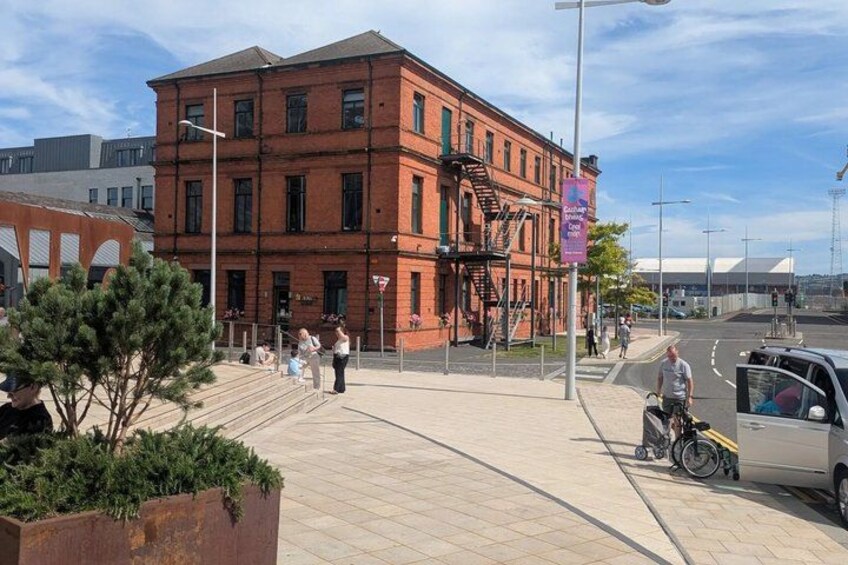 A red brick building with a fire escape, a pedestrian walkway, and a parked motorcycle. 2