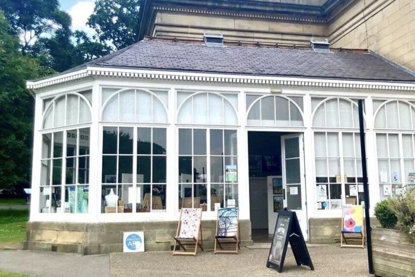 A glass conservatory with a white frame, displaying artwork on easels. 4