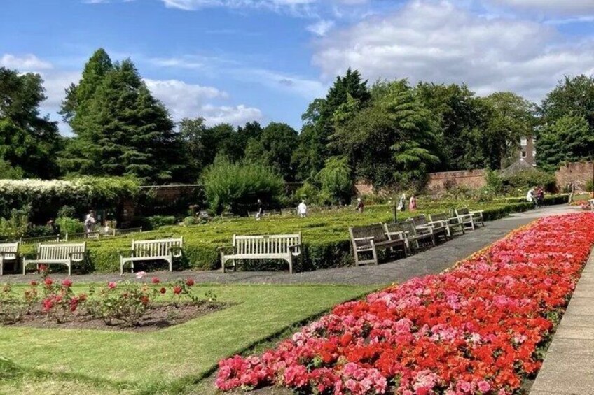 A park with benches, flower beds, and trees. 5