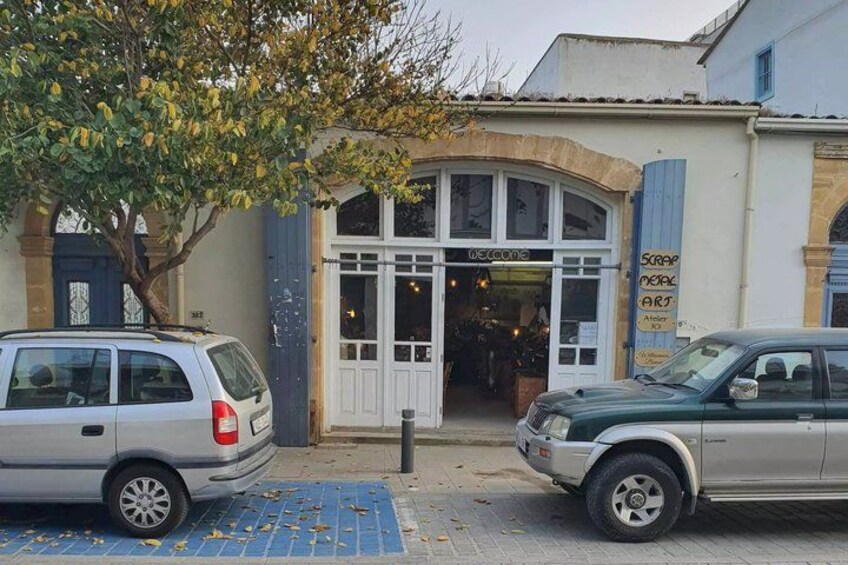 A building with a 'Welcome' sign, a tree, and two parked cars. 2
