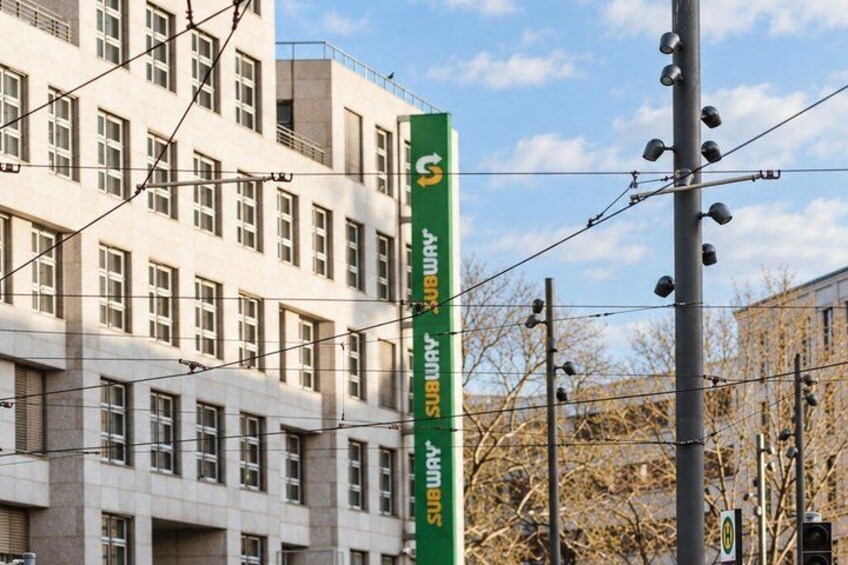 A Subway sign in front of a building with multiple windows and a clear sky. 4