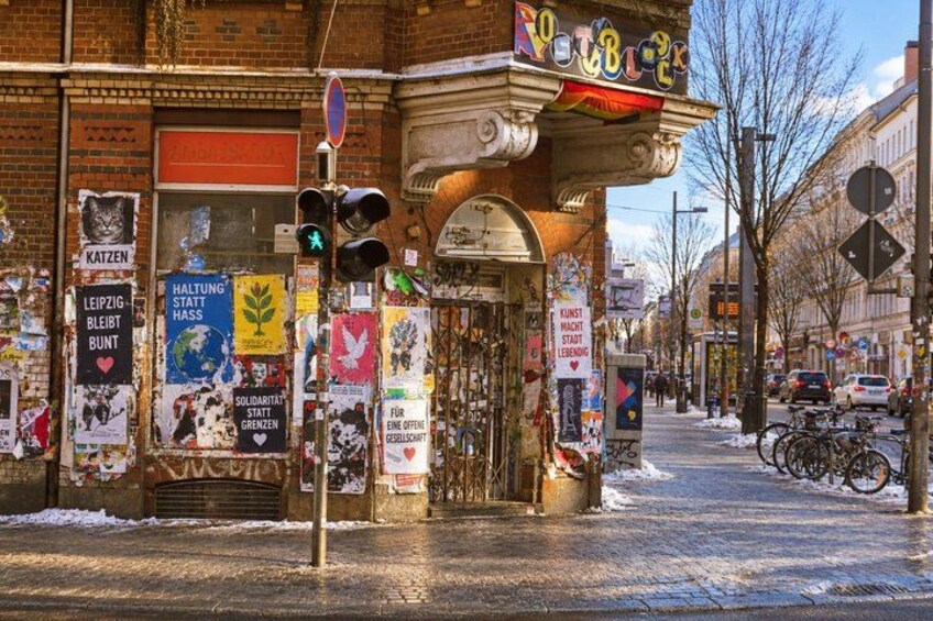 A street with a shop displaying various posters and signs, a traffic light, and a bicycle parked on the sidewalk. 3