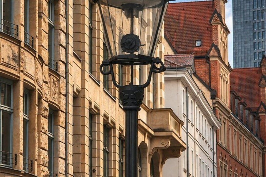 A street lamp with ornate details, a building with classical architecture, and a red-roofed structure in the background. 2