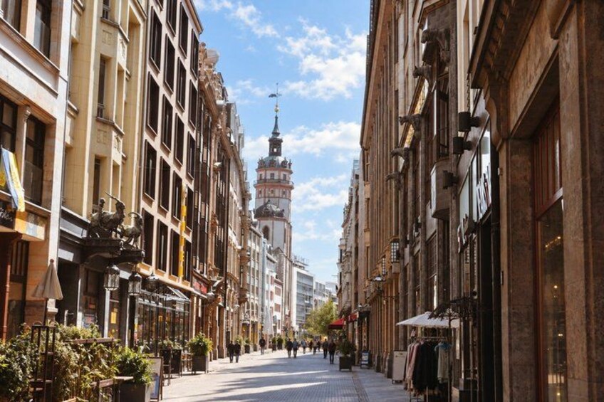 A street lined with historic buildings, a prominent tower, and a clear sky. 5