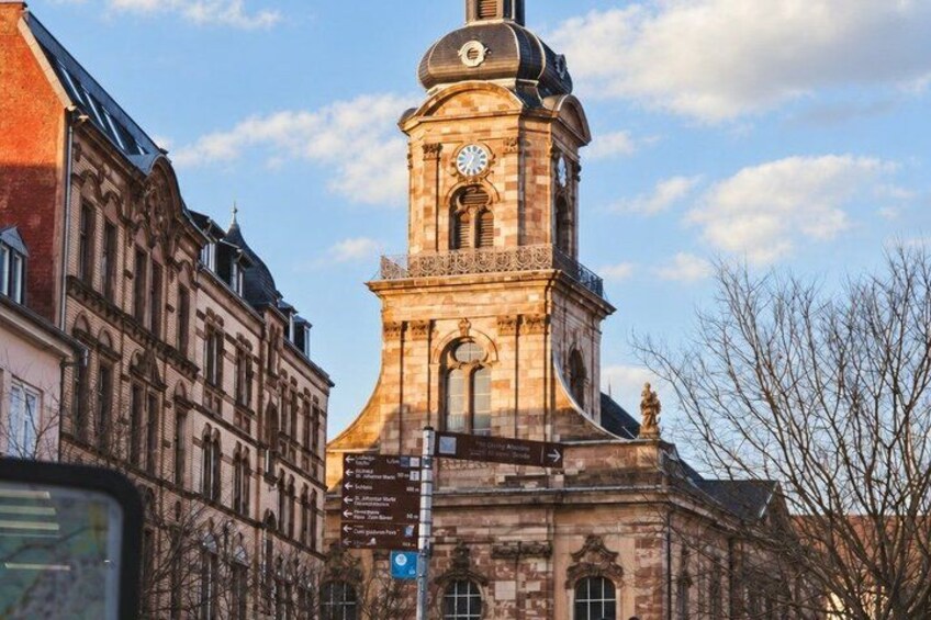 A historic building with a clock tower, a street sign, and bare trees. 4