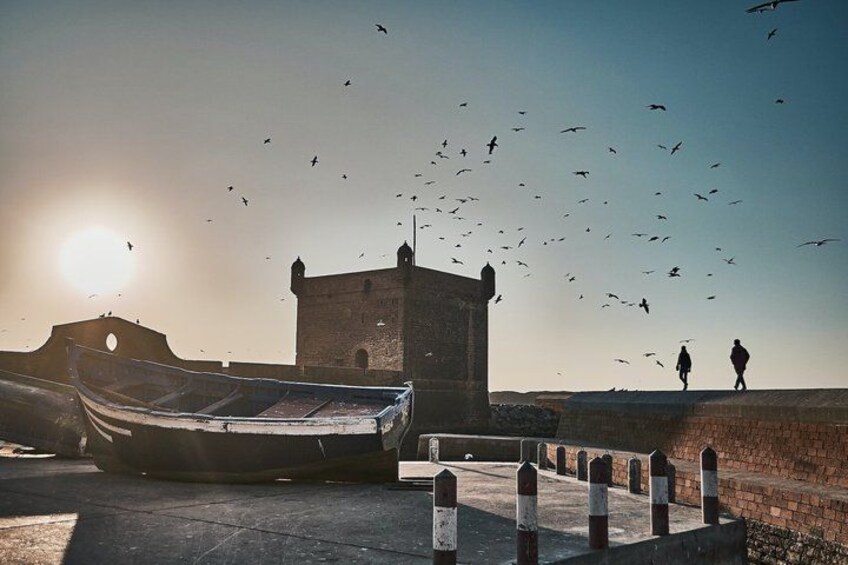 A boat, a tower, and two people walking on a ledge. 5