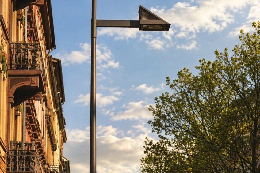 A street lamp, a building with ornate balconies, and a tree with green leaves. 3
