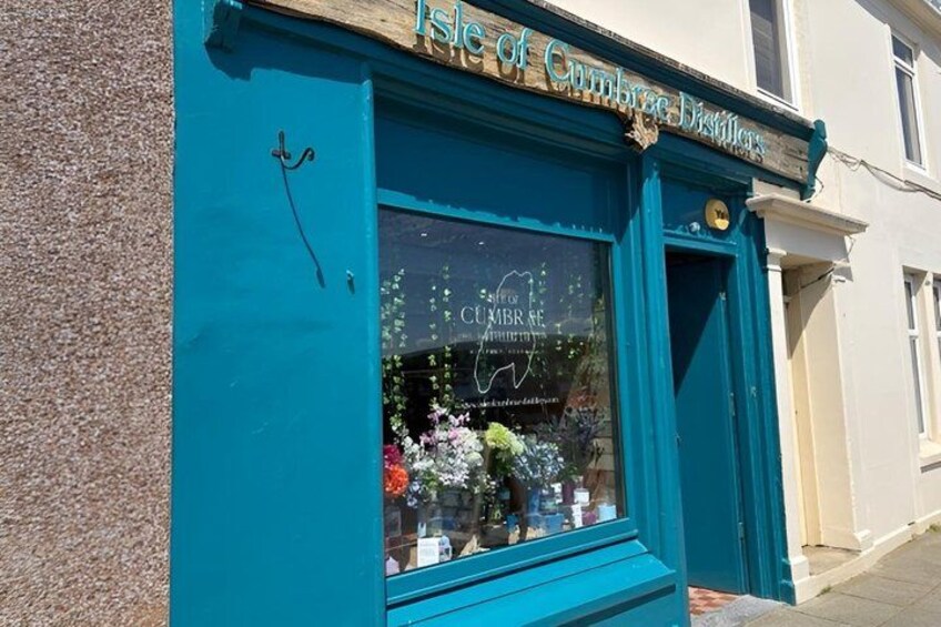 A teal storefront with a sign reading 'Isle of Cumbrae Distilleries.' 2