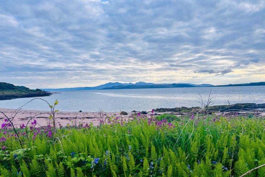 A coastal landscape with a beach, mountains in the distance, and a cloudy sky. 5