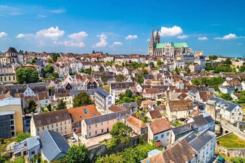 A cityscape with historic buildings, a prominent cathedral with twin spires, and a clear blue sky. 1