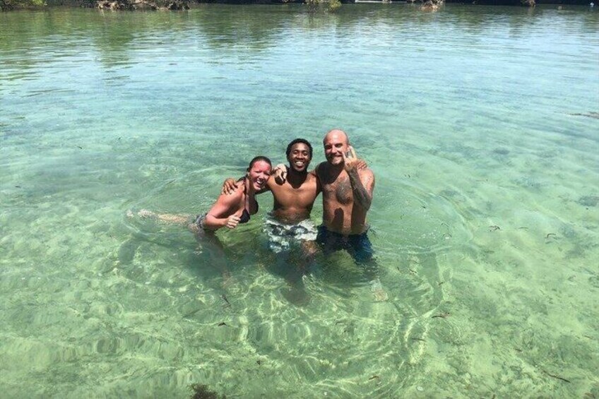 Three people in clear water, possibly a natural pool or lake. 3