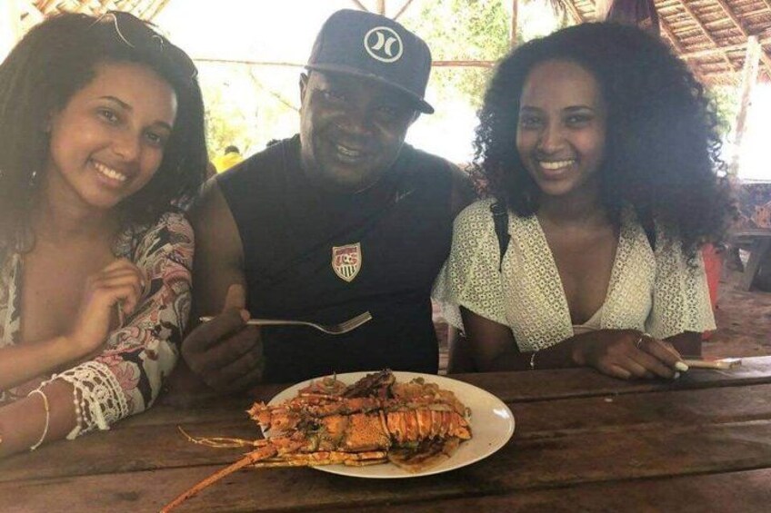 Three people sitting at a wooden table with a plate of lobster in front of them. 2