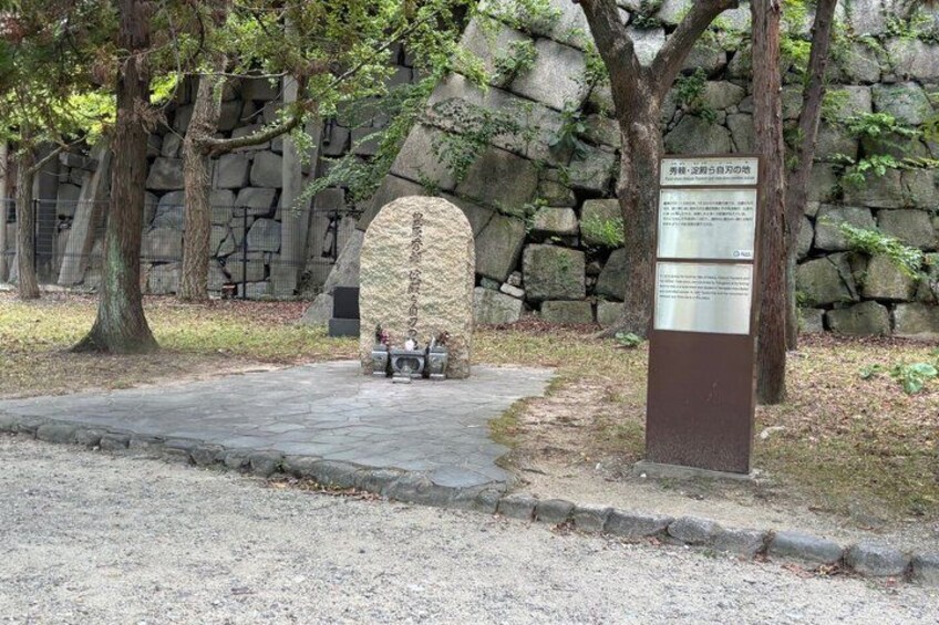 A stone monument, a stone wall, and a bench in a park. 5
