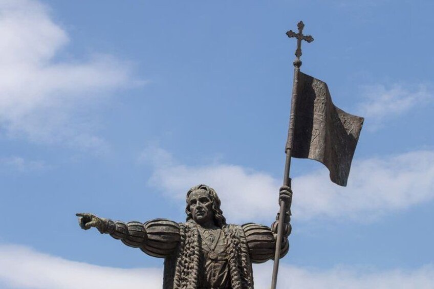 A statue with outstretched arms, a flag, and a cross. 4