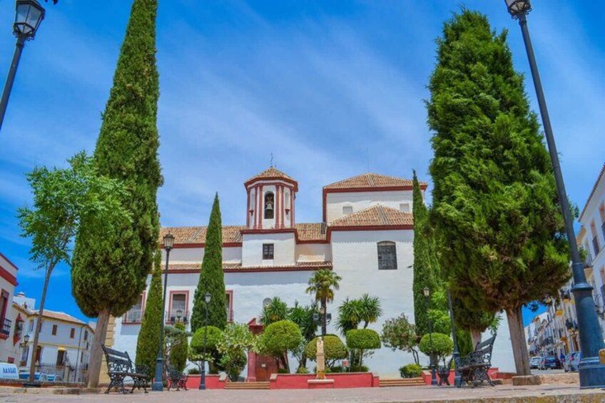 A historic church with a bell tower, surrounded by tall trees and a clear blue sky. 5