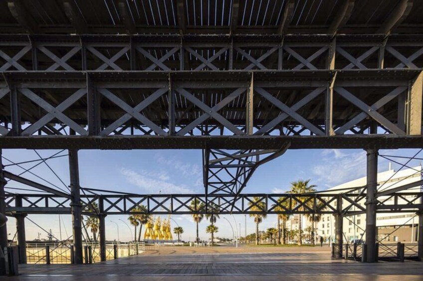 A metal framework structure with a clear sky and palm trees in the background. 3
