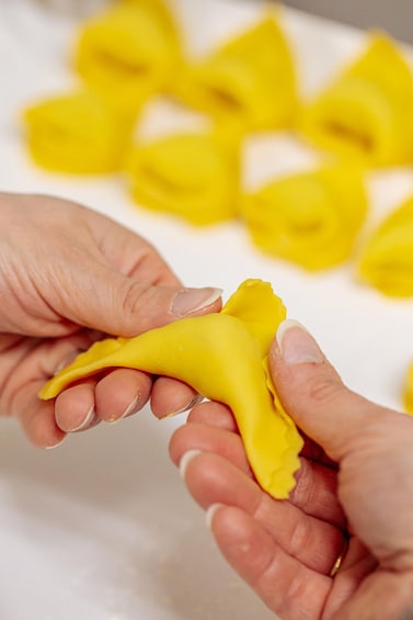 A person holding a yellow object, possibly dough, with other yellow objects in the background. 3
