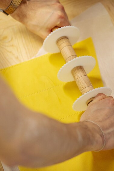 A person sewing with a yellow fabric and wooden spools. 1