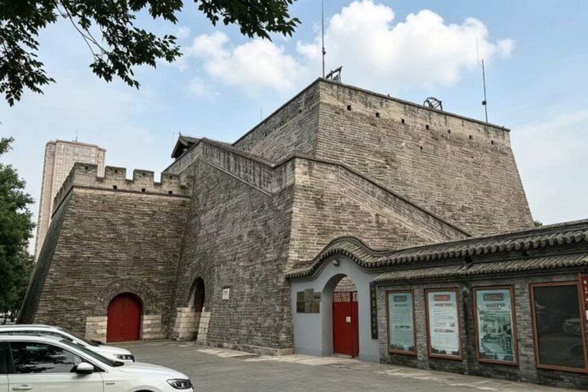 A historic stone building with a red door and a brick wall. 2
