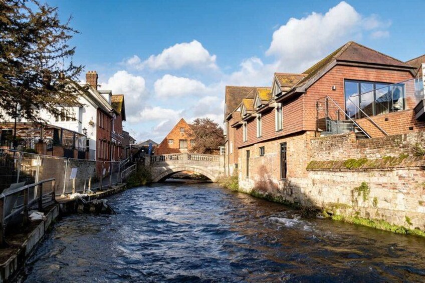A river with buildings on both sides, a bridge, and a clear sky. 4