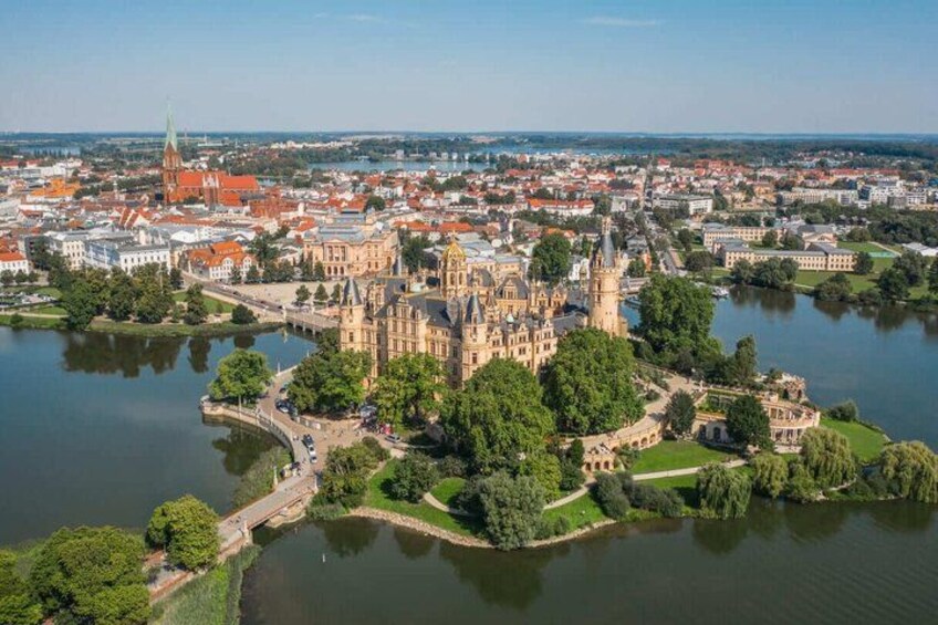 A historic castle surrounded by water, with a cityscape in the background. 1