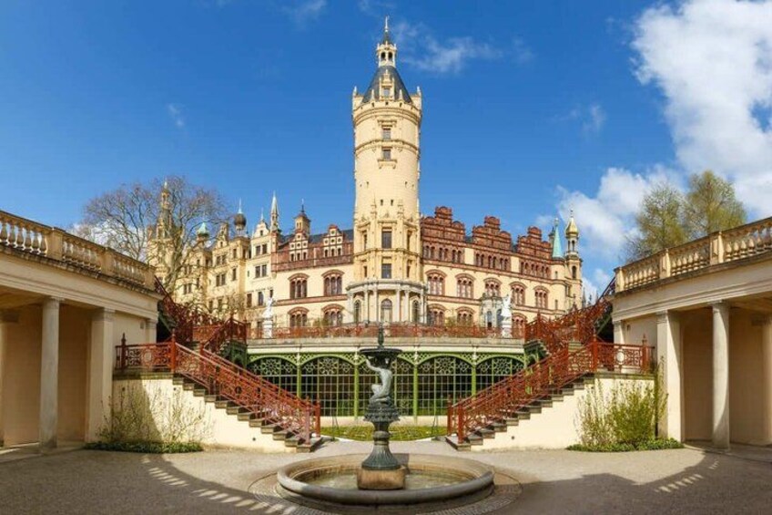 A historic building with a tower, a fountain, and a red staircase. 4