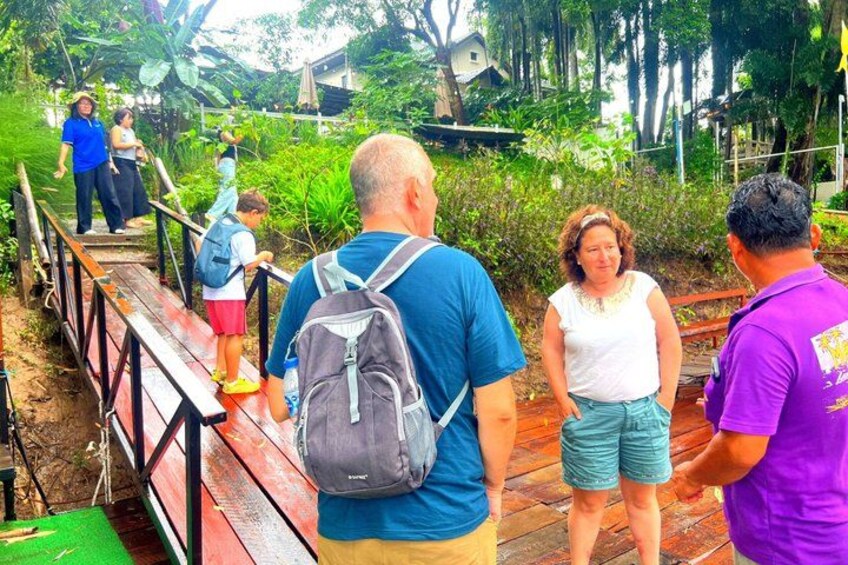 People walking on a wooden bridge in a green, tropical setting. 4