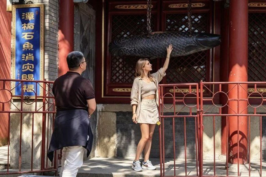 A person reaching out to touch a large fish sculpture. 5
