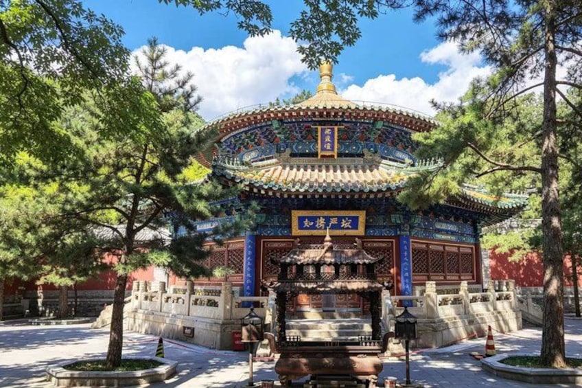A traditional Chinese pavilion with a tiled roof, surrounded by trees and a stone pathway. 2