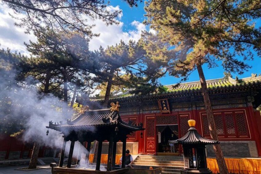 A traditional building with a tiled roof, a stone staircase, and a pagoda-like structure emitting steam. 4