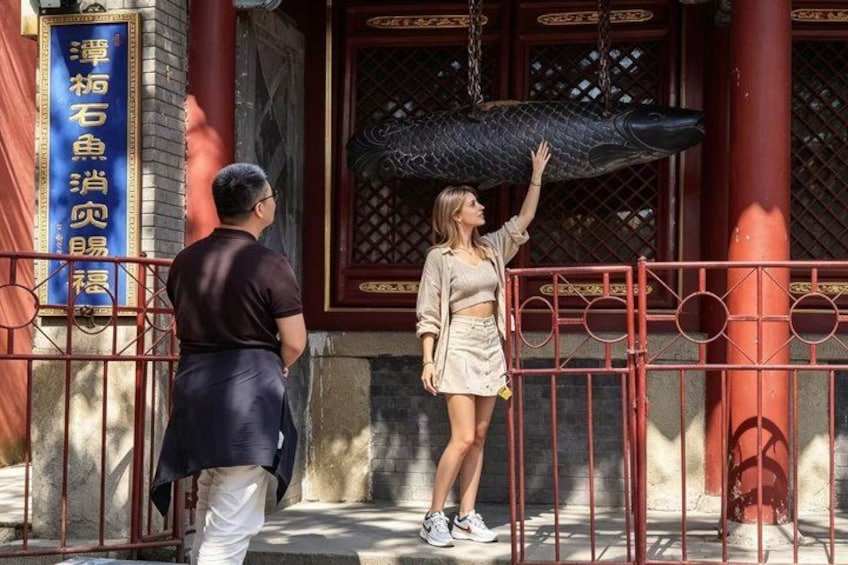 A person reaching out to touch a large fish sculpture. 1