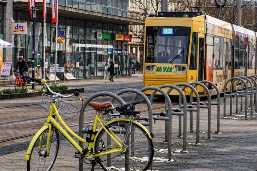 A yellow tram, a yellow bicycle, and a tram stop with a metal fence. 5