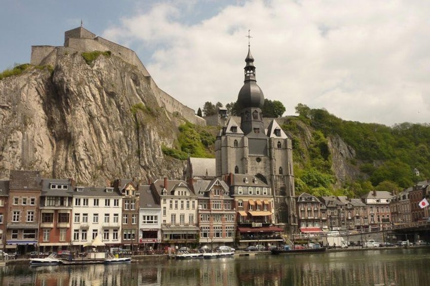 A historic town with a prominent church, a castle on a hill, and a waterfront with boats. 1