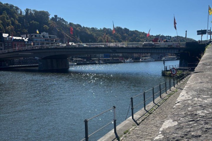 A bridge over a river, a boat docked on the riverbank, and flags on a hill. 2